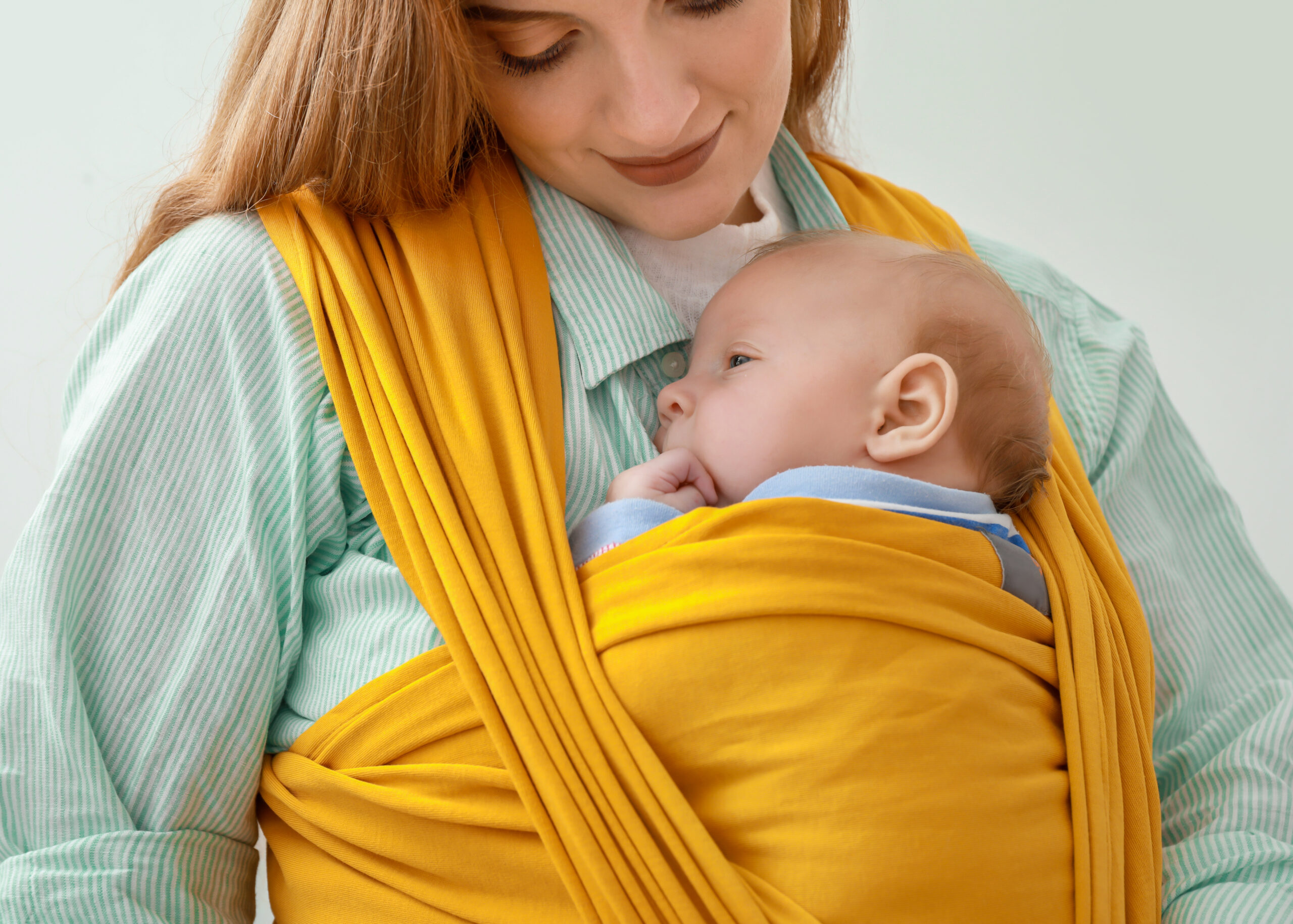 Young mother with little baby in sling on white background, closeup